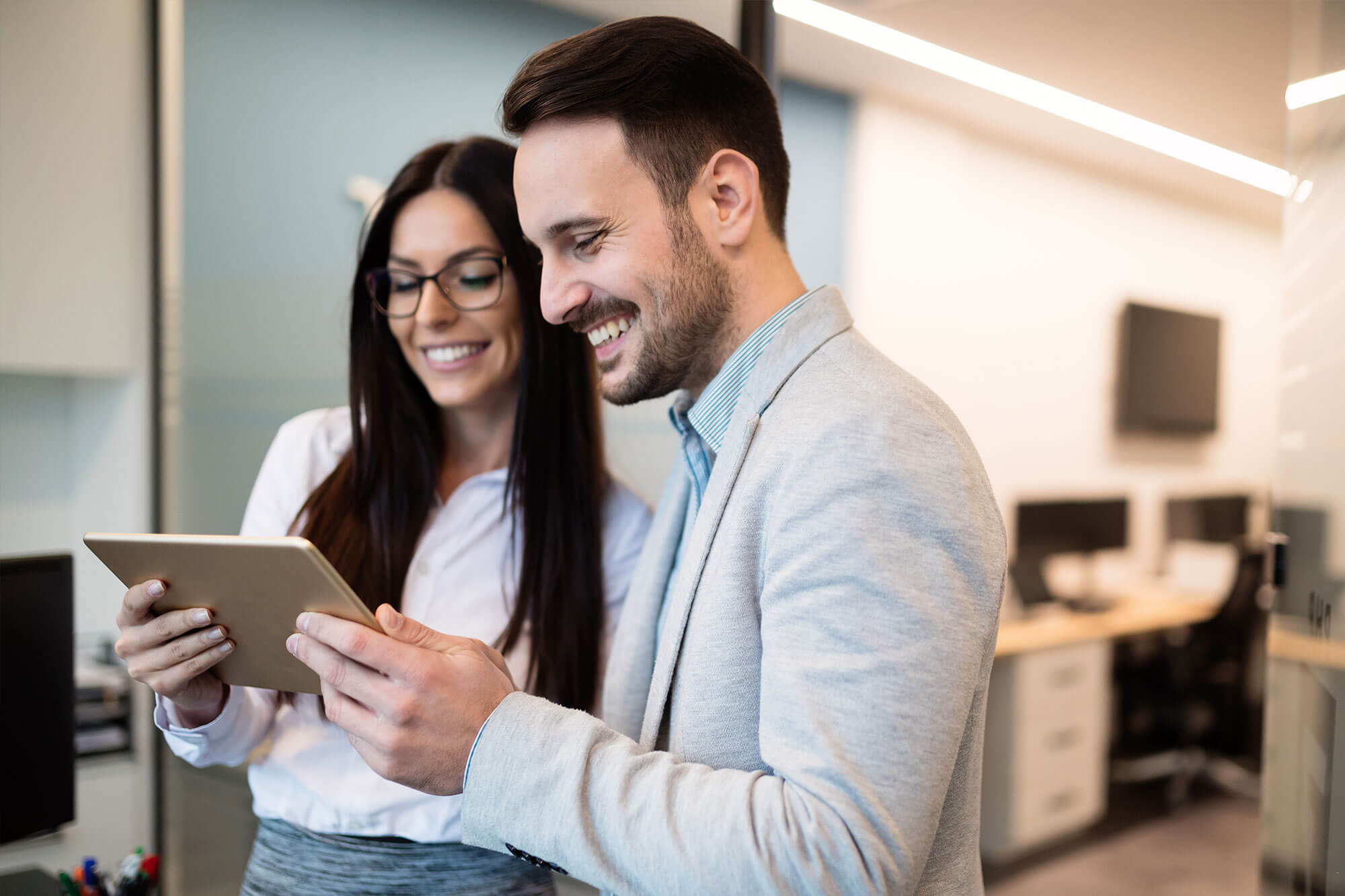 two people looking at a tablet in an office