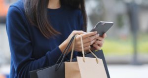 woman with shopping bags searching on smartphone